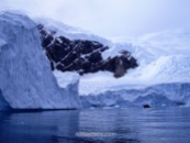 El glaciar se pierde de vista por encima de las montañas. En el agua se ve una de nuestras lanchas zodiac